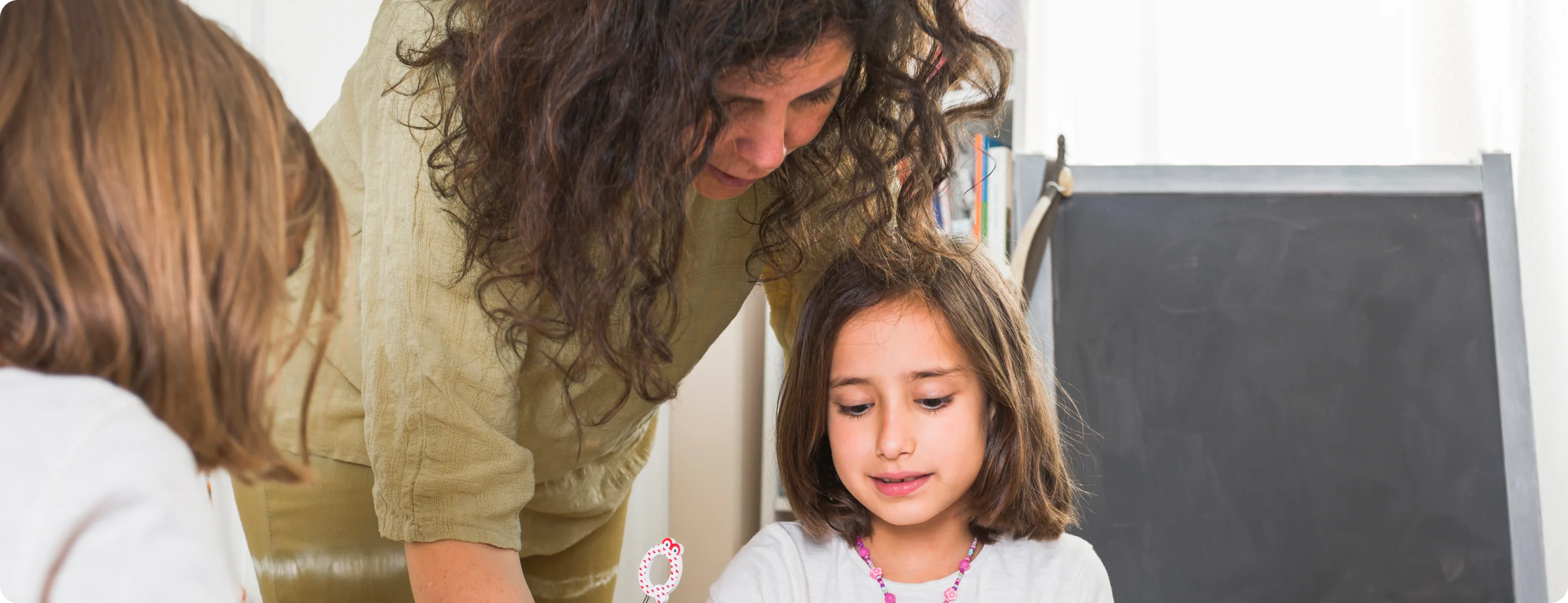 Teacher helping a student in a classroom, showing support for children with learning needs.